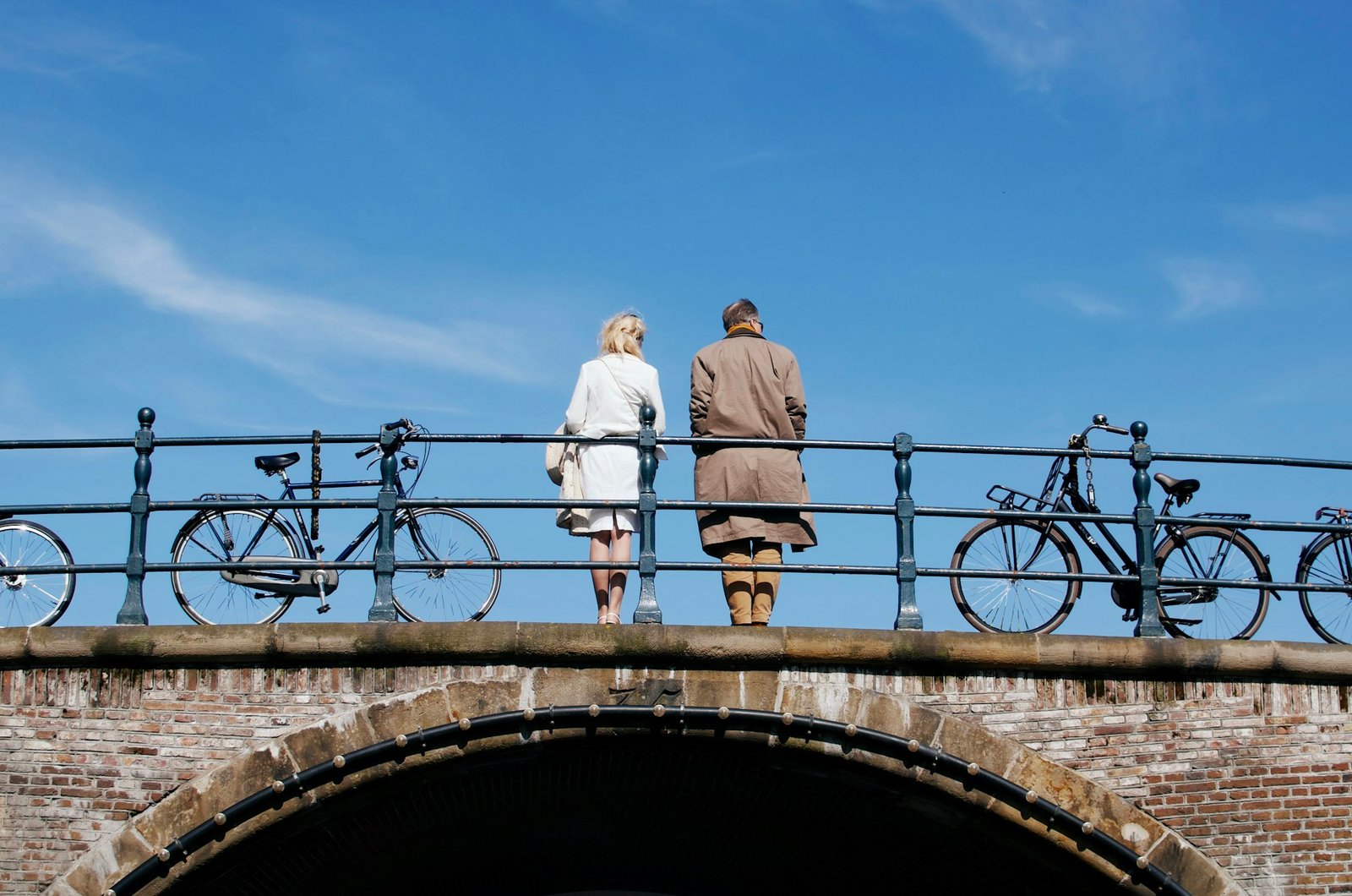 Een ouder stel loopt over een brug bij een gracht