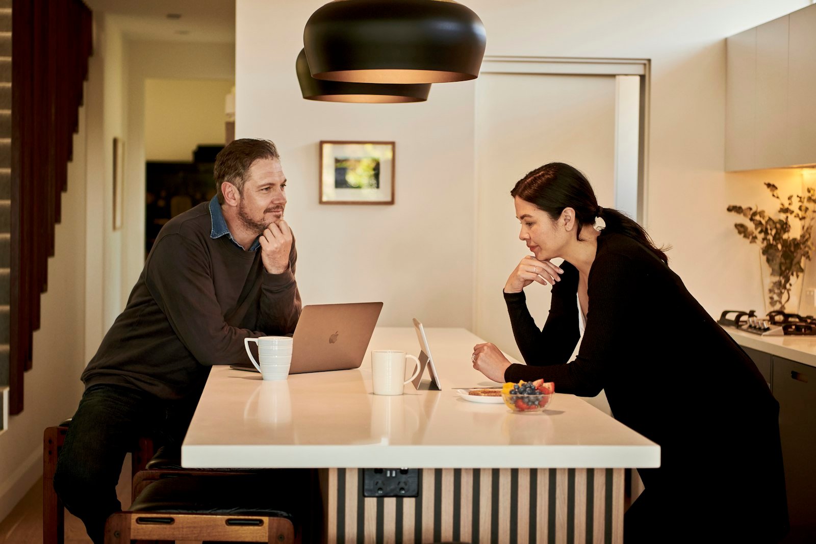 Een adviseur en een klant in gesprek aan een tafel met een laptop