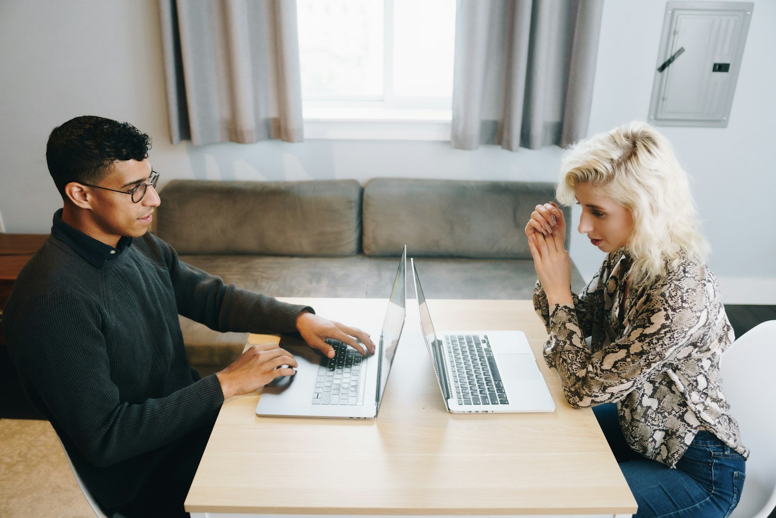 Twee mensen aan tafel met hun laptops, in gesprek